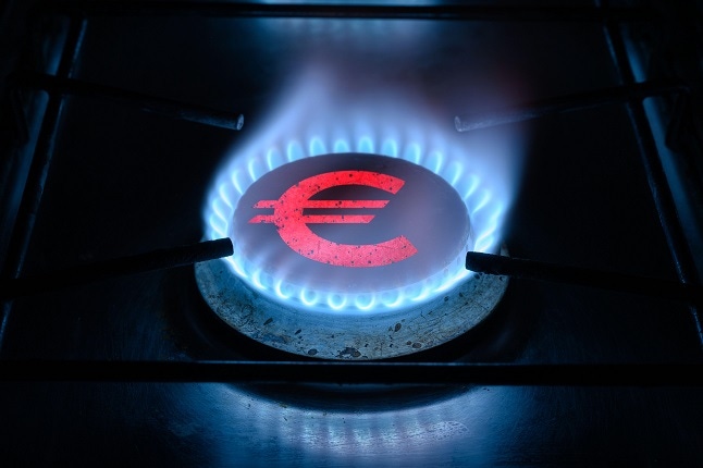 Euro sign, European money symbol on home gas stove. Blue propane flame and currency. Concept of energy crisis