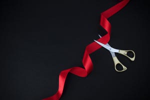 scissors cutting red ribbon with black background