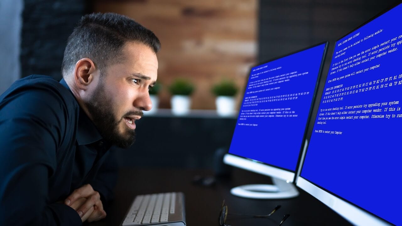 Worried Man At Computer With System Failure Screen At The Workplace Worried Man At Computer With System Failure Screen At The Workplace