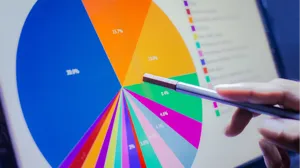 A stylus is held in front of a pie chart on a screen A stylus is held in front of a pie chart on a screen