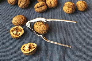 Walnuts with nutcracker. Cracking nuts on a dark background. Walnuts with nutcracker. Cracking nuts on a dark background.