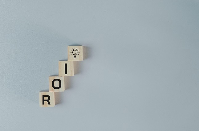 Wooden cubes with ROI Return on Investment symbol on background 