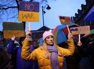 A demonstrator in a yellow jacket and blue scarf attends a vigil after Russian President Putin ordered invasion of Ukraine.