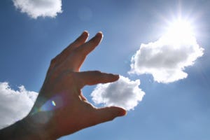 hand appearing to carefully pluck off a piece of a cloud, breaking it in two