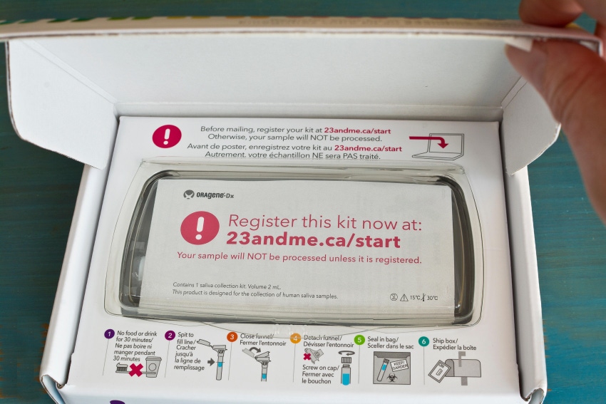 Inside of 23andMe home DNA test kit. Hand opening box of genetic testing hit.