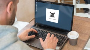 IT worker looking at a laptop with ransomware on it IT worker looking at a laptop with ransomware on it