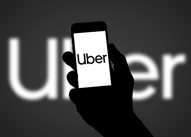 hand in the dark holding a cell phone with Uber Logo