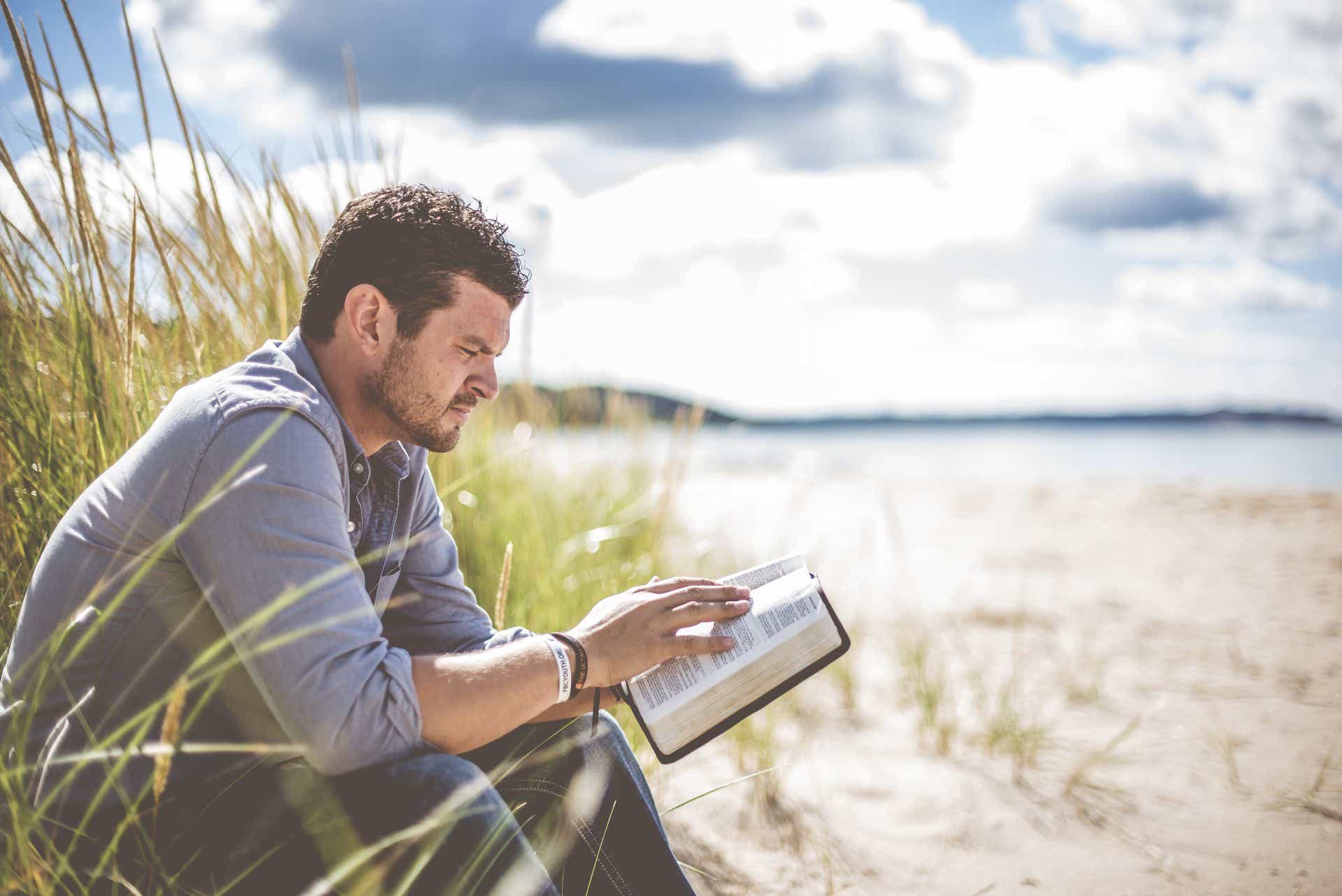 A man with reading on a beach on holiday.