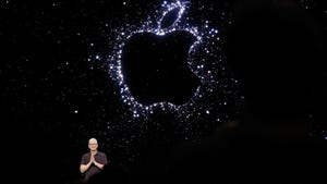 A man in glasses stood in front of a large black and white Apple logo