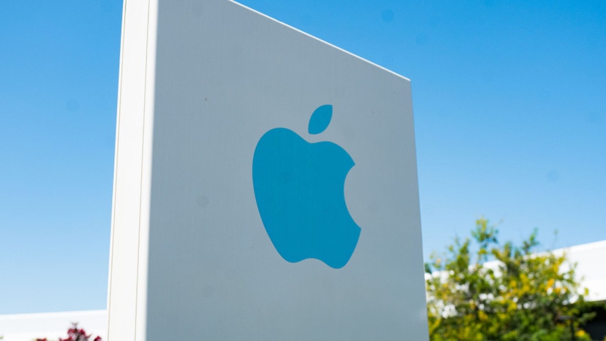 Close-up of blue logo on sign with facade of headquarters buildings in background near the headquarters of Apple Computers in the Silicon Valley