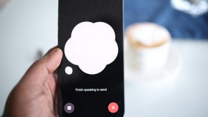 A hand holding up a phone displaying ChatGPT's new voice capabilities