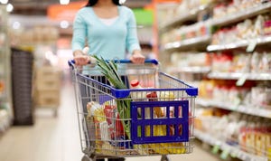 A stock photo of a woman pushing a shopping cart in a supermarket