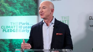 A bald man in a suit talking at a podium