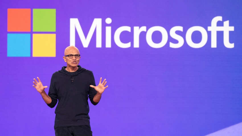 A man stands in front of the Microsoft logo on a purple background