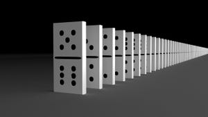 Stock image of dominoes lined up and ready to be knocked over on a black background