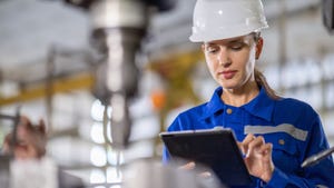 Engineer controls a tablet device to inspect the drilling machine in the factory.