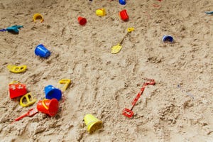 Stock image of sand with children's beach toys scattered on top 