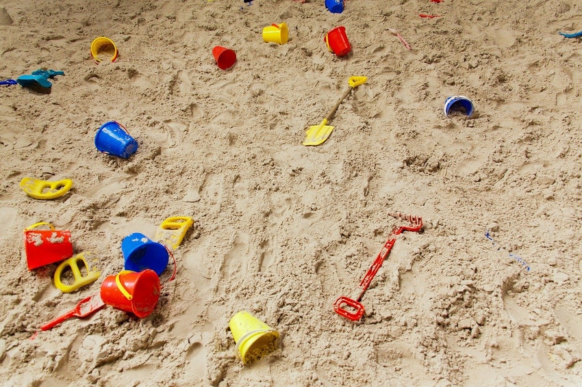 Stock image of sand with children's beach toys scattered on top 