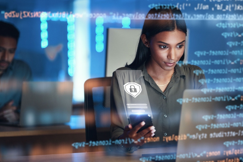 A woman at a laptop and on a phone with an overprojection of screen images