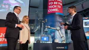 Three people standing talking in front of a robot arm
