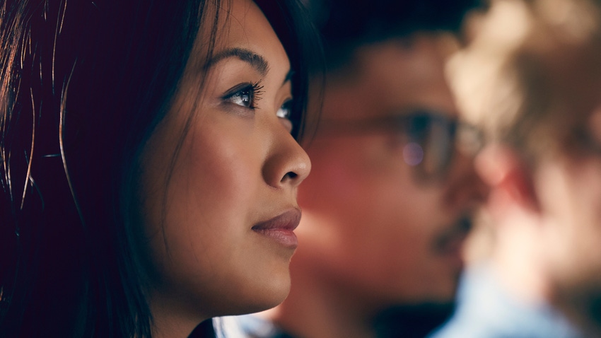 Asian woman's right profile with blurred profiles of male faces to her left