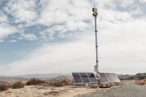 Image of a communications pole in an empty landscape, with solar panels