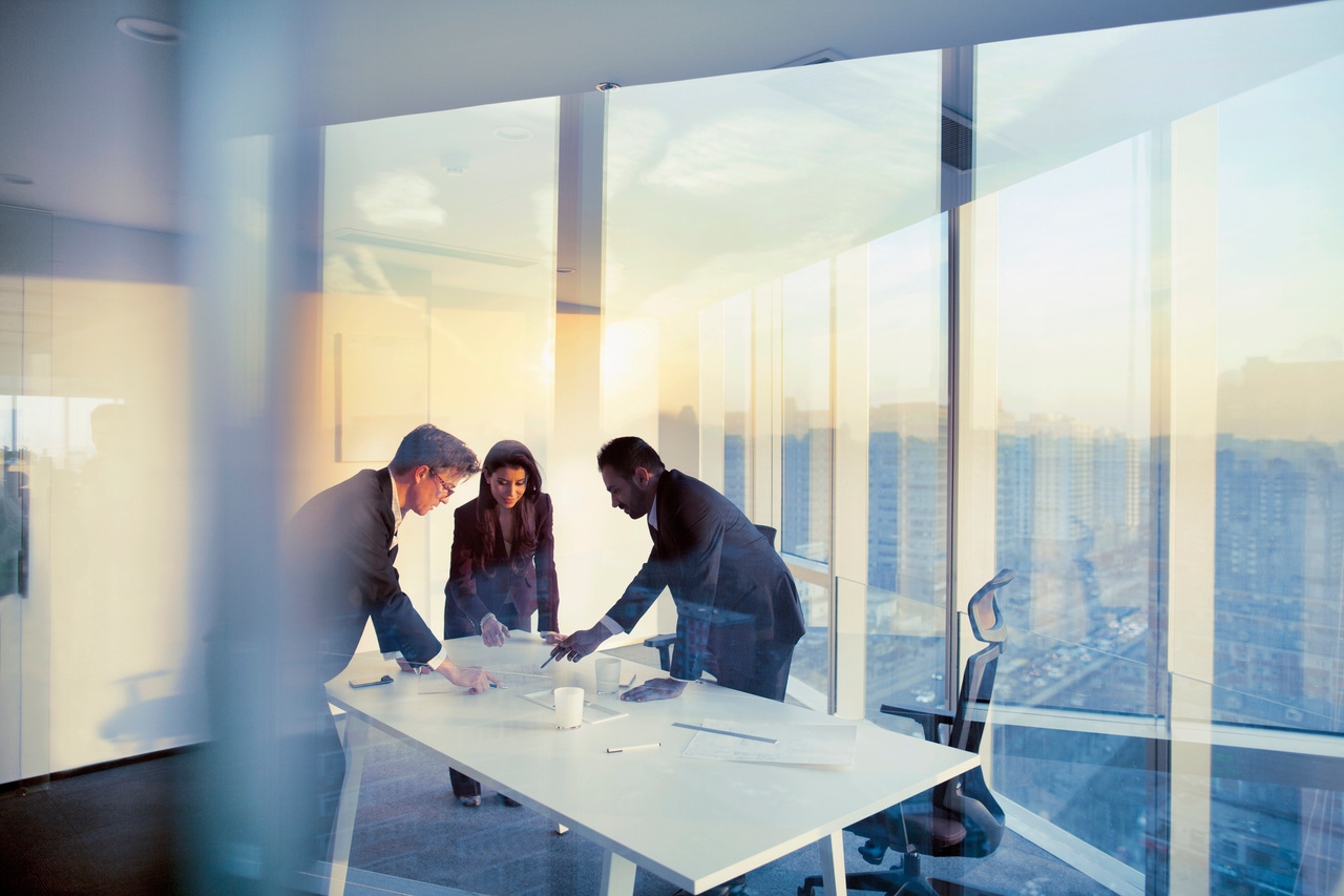 Executives stand around a table in an office