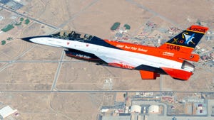 An orange, black, and white fighter jet takes to the skies