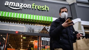 Customers carry their purchases as they leave from a branch of Amazon Fresh