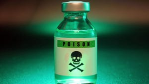A vial of poison with a skull on it illuminated by a green light