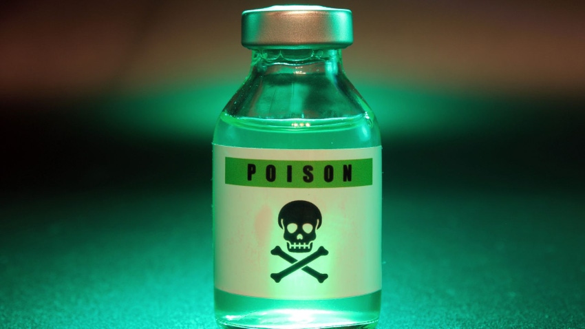 A vial of poison with a skull on it illuminated by a green light