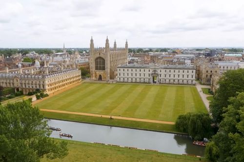 University building surrounded by mown grass and a moat