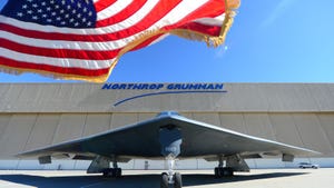 A Northrop Grumman-made B-2 stealth bomber on a runway under the company's logo and an American flag