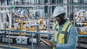Engineer in high visibility vest using tablet computer in an automotive industrial facility