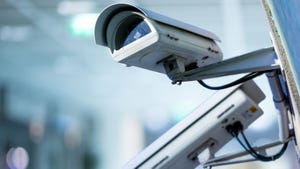 Closeup image of a grey CCTV security camera with blurred background