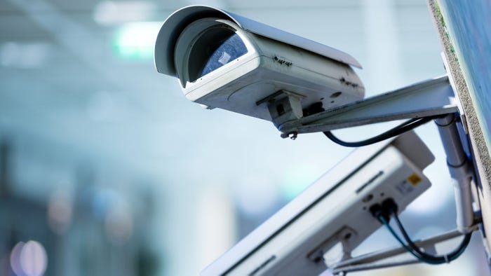 Closeup image of a grey CCTV security camera with blurred background
