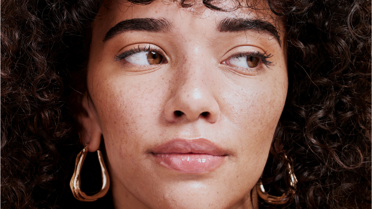 Gros plan sur le visage d’une femme aux cheveux noirs bouclés, regardant sur le côté.