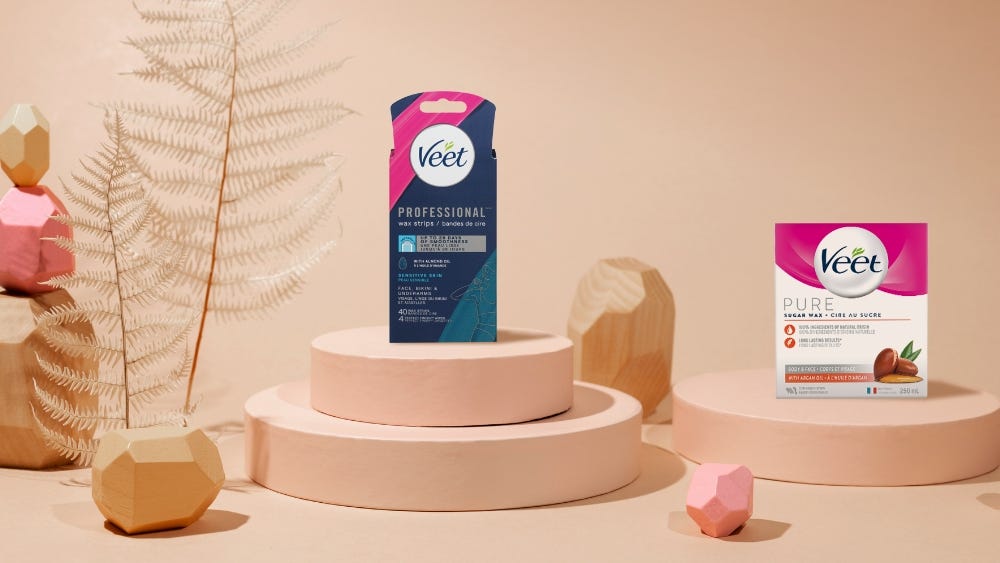 Les bandes de cire Veetᴹᴰ Professional pour le visage et les bandes de cire Veetᴹᴰ PURE pour le visage, sur des rehausseurs de couleur pêche, avec des galets géométriques or et pêche.