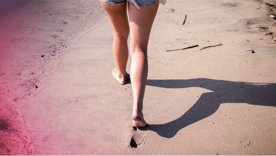 Une femme marchant pieds nus sur la plage.
