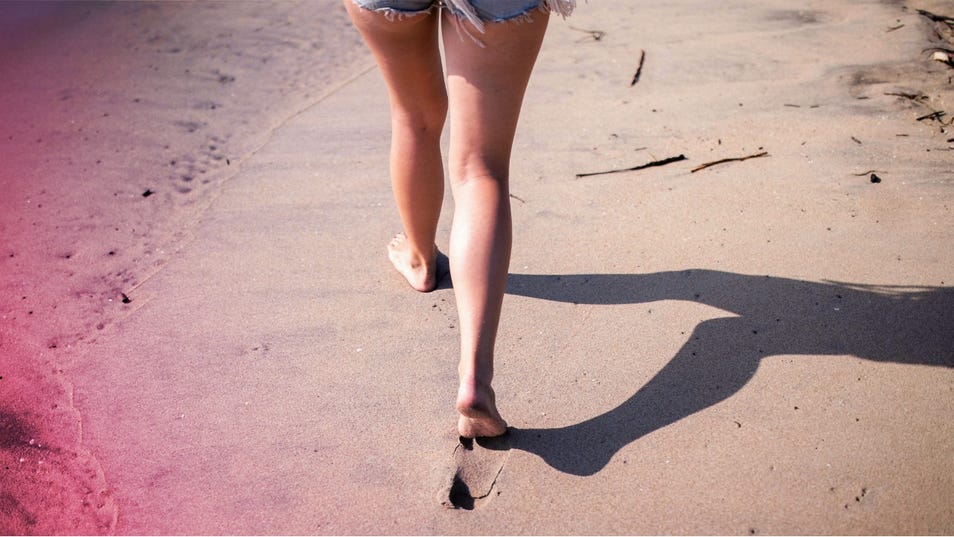 Une femme marchant pieds nus sur la plage.