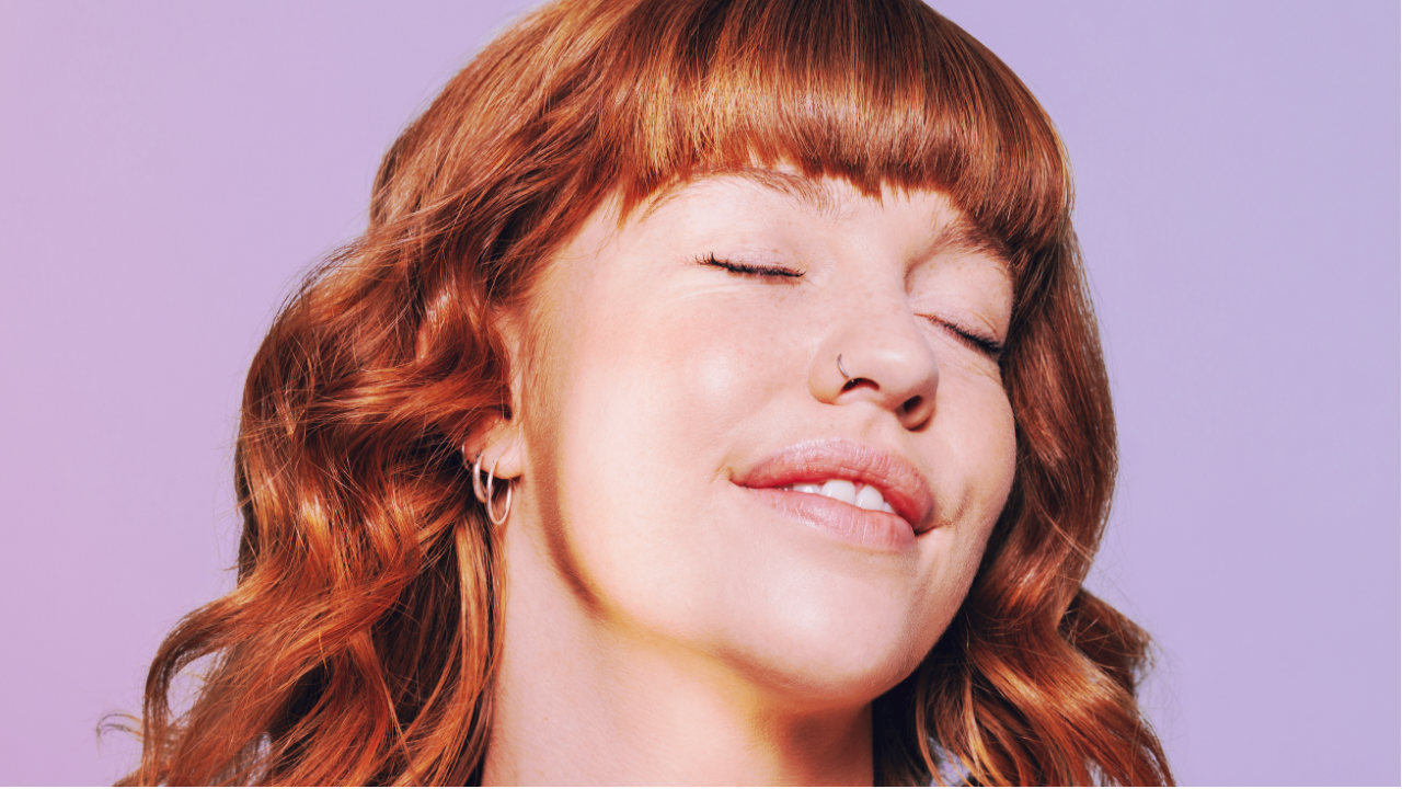 Close-up of woman with glowing skin smiling with her eyes closed.