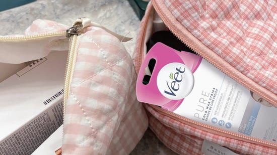 Contre-plongée d’une trousse de maquillage rose à carreaux avec un produit d’épilation à la cire Veet en dépassant légèrement.