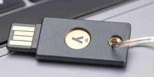 A black hardware authentication key called Yubikey is on the laptop keyboard.
