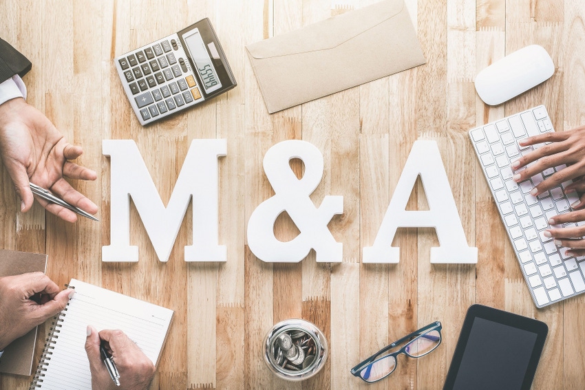 The letters m&a on a table, surrounded by hands