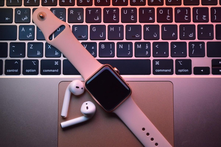 an image of loose AirPods and an Apple Watch laid out on the touchpad and keyboard of a Mac.