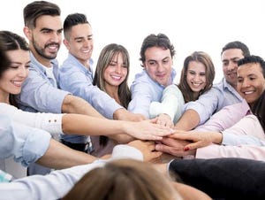 A group of people with hands together in the middle to show teamwork.