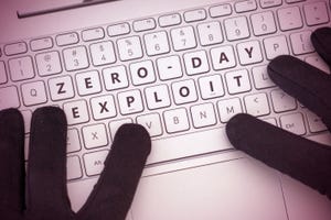 White computer keyboard with "zero-day exploit" spelled outon keys and gloved fingers typing