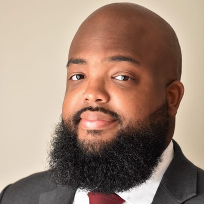 Jordan Burris, senior director of product market strategy for the public sector at Socure, wears a suit and a full beard
