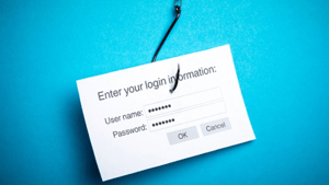 Black fishhook that has hooked a card that says "Enter your login information" with user name and password fields filled Black fishhook that has hooked a card that says "Enter your login information" with user name and password fields filled