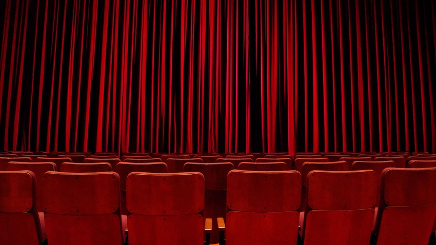 Closed, red curtains in a theater in front of seating